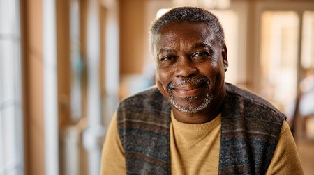 Closeup of man in plaid vest smiling at home
