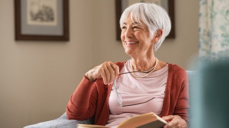 Senior woman smiling while reading at home