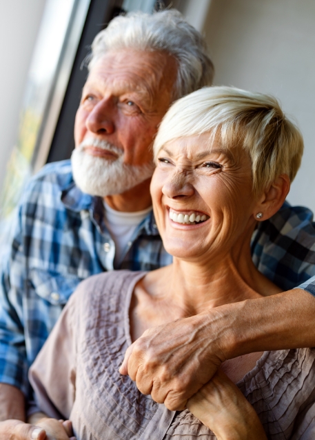 Senior couple hugging and looking out of a window together