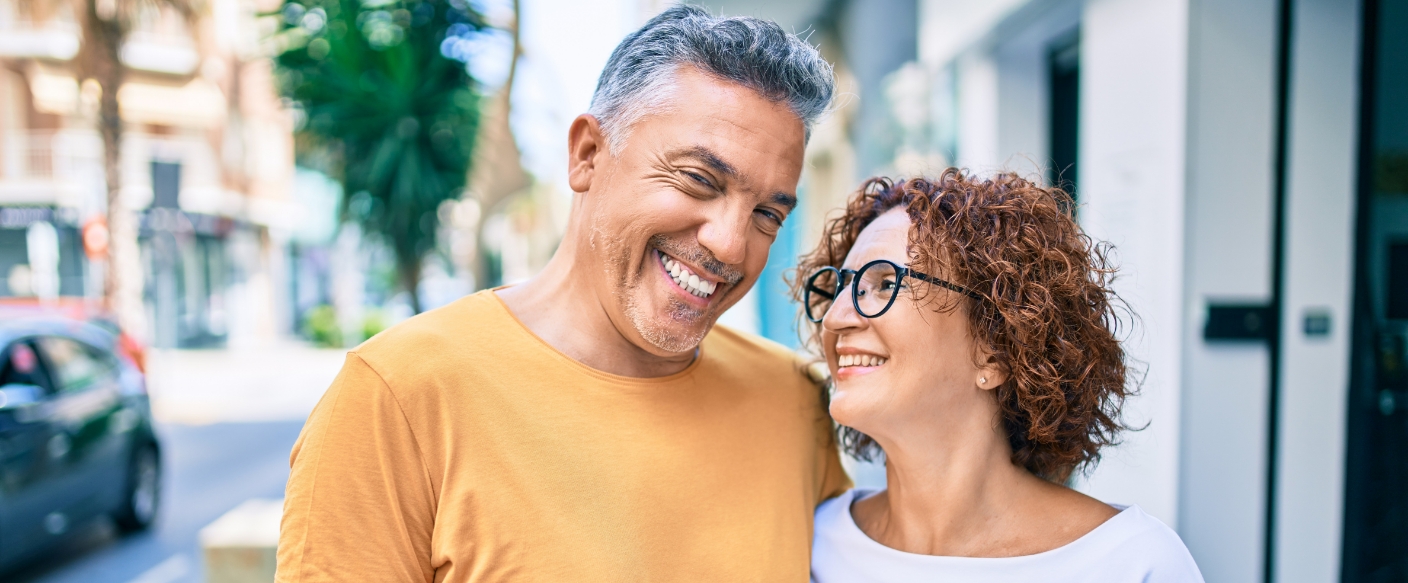 Couple on a city sidewalk smiling with dental implants in Tampa