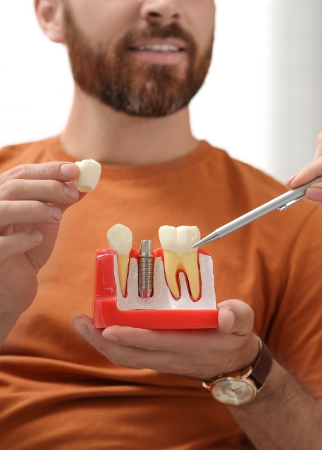 Dentist showing a model of a dental implant to a patient