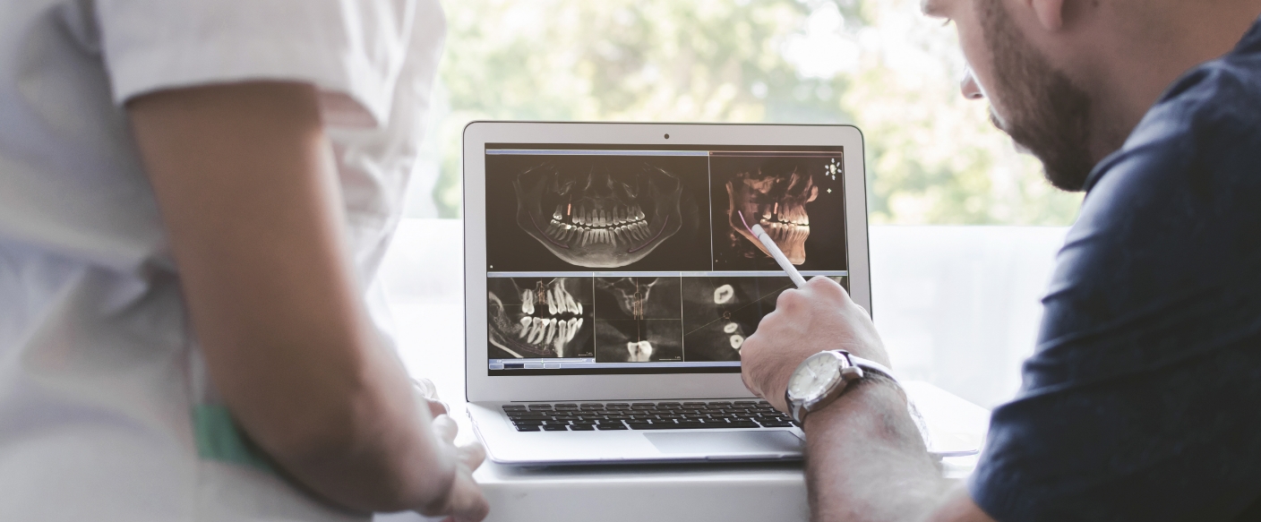 Dentist showing a patient a screen with digital x rays and scans of teeth