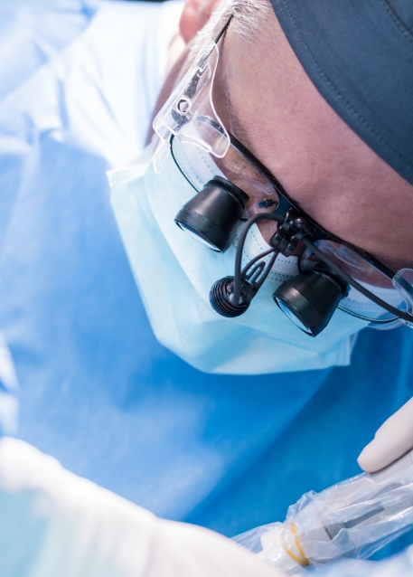 Implant dentist wearing dental binoculars while treating a patient