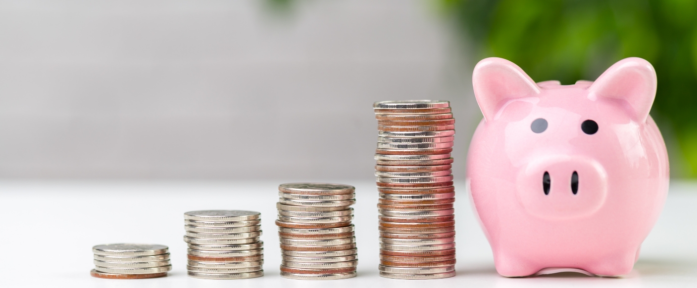 Pink piggy bank next to four stacks of coins