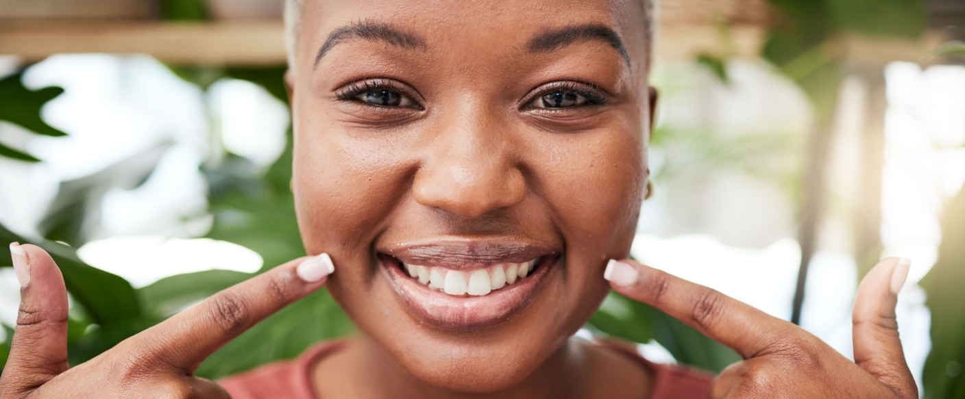 Woman pointing to her smile after getting dental implants in Tampa