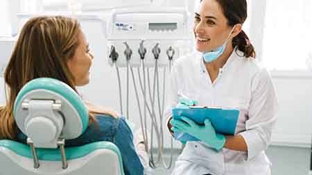 Dentist smiling at patient while taking notes on clipboard