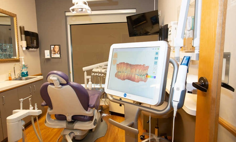 Dental treatment room with a screen showing a digital model of a row of teeth