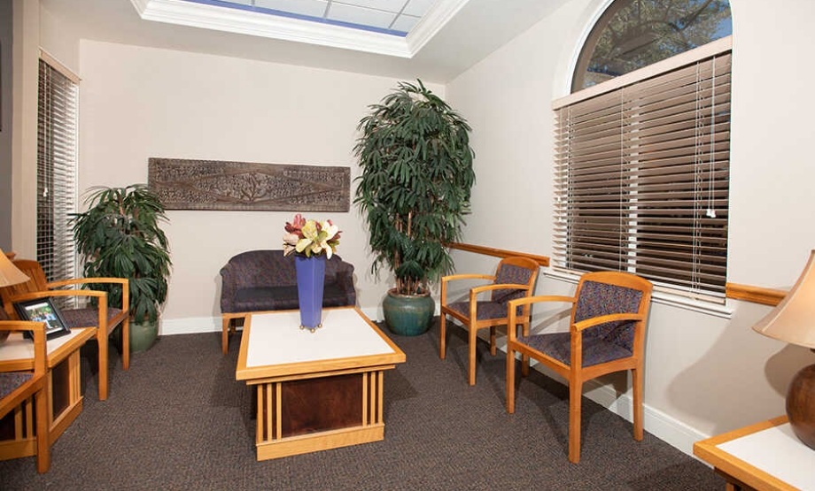 Waiting area with several chairs and two ferns