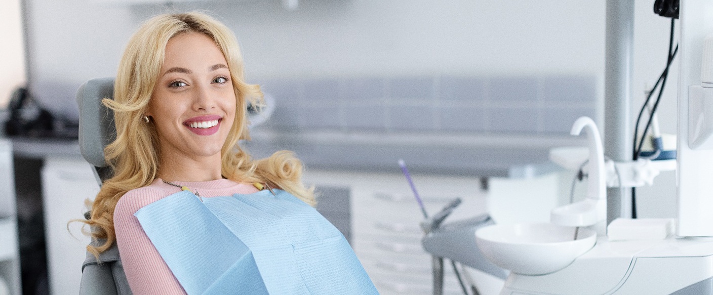 Blonde woman sitting in treatment chair and smiling