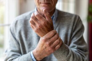 Man with arthritis holding wrist in pain.